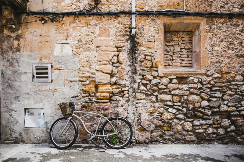 A bicycle waits against an old stone wall.