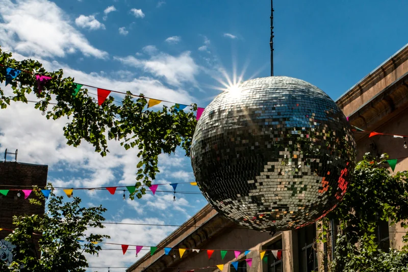 A silver mirror ball catches sunlight against a blue sky.