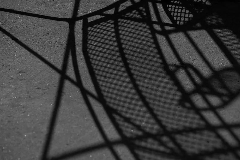 A chair’s shadow stretches across the ground.